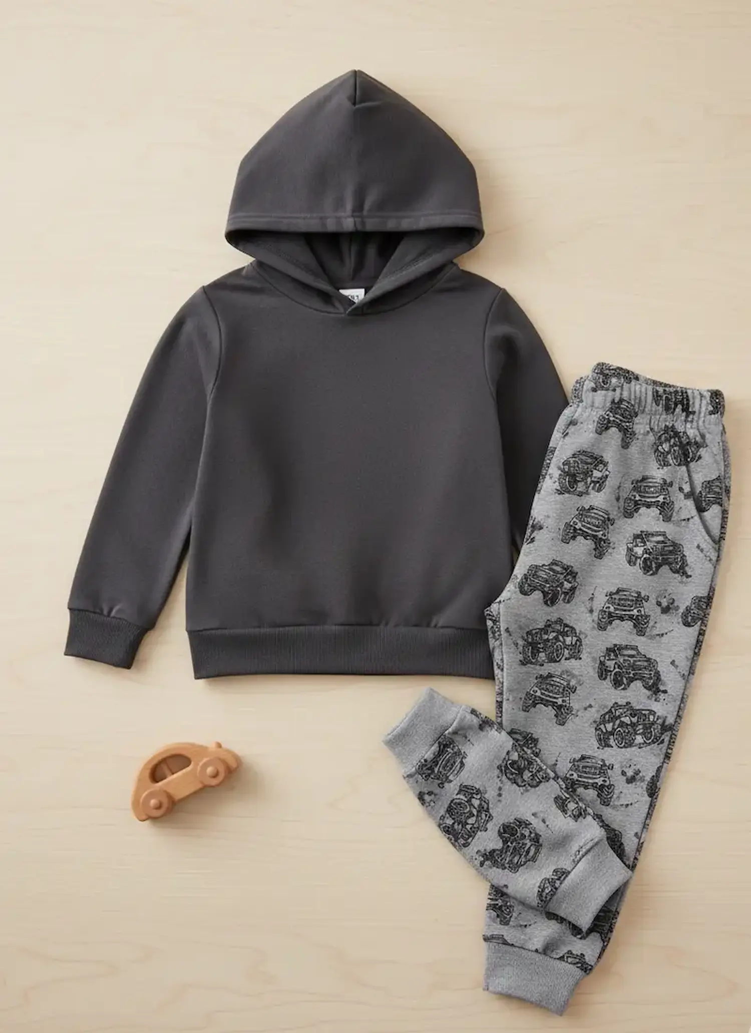 Sweatshirtstoff als Meterware verarbeitet zu einem Kinder-Set aus anthrazitfarbenem Hoodie und grauer Jogginghose mit Monstertruck-Muster.