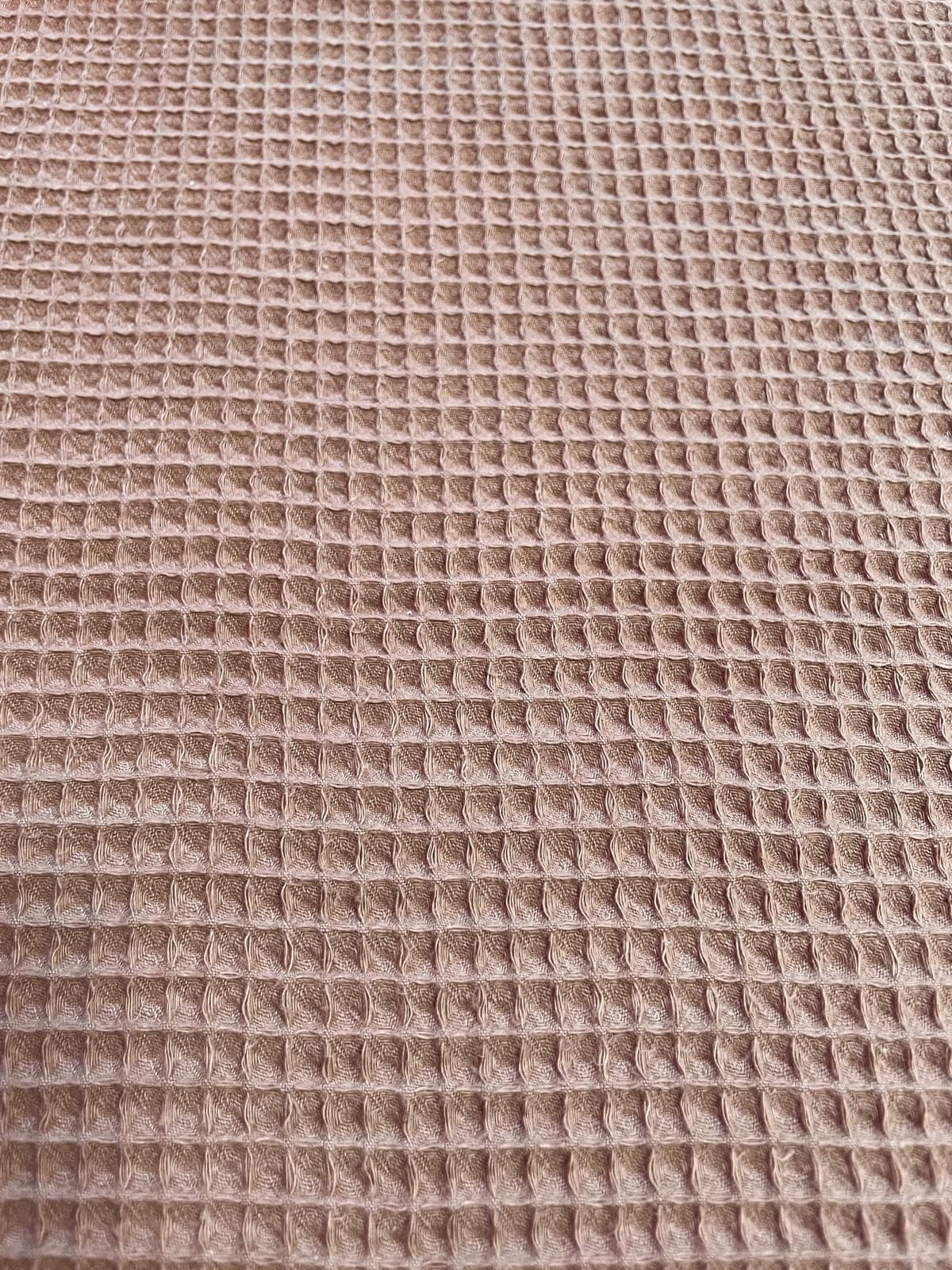 Nahaufnahme von braunem Waffelpique Stoff als Meterware mit charakteristischer Waffelstruktur für Decken, Handtücher und herbstliche DIY-Projekte.