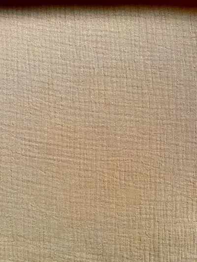 Struktur von warm-beigem Musselin-Stoff aus 100% Baumwolle, 130g/m² Gewicht und 140cm Breite für Näharbeiten.