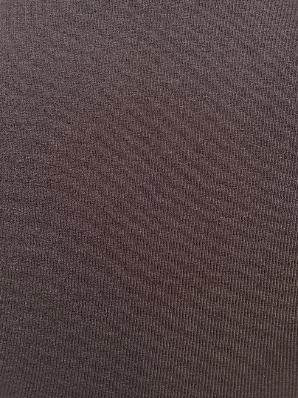 Nahaufnahme der feinen Strickstruktur eines dunkelbraunen Jersey-Stoffes in Mocca, blickdichte Qualität aus 92% Baumwolle und 8% Elasthan.