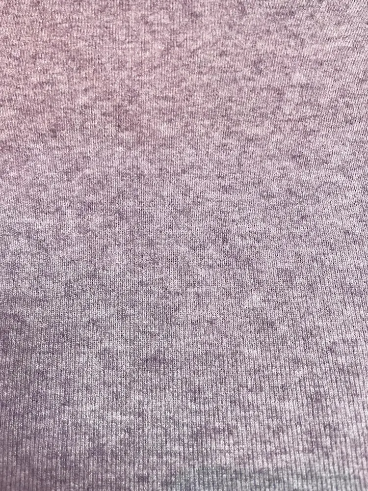 Ein weicher Strickstoff in Altlila (Mauve) mit feiner vertikaler Rippenstruktur und Melange-Optik. Die melierte Oberfläche verleiht dem elastischen Material eine hochwertige Tiefe. Ideal für herbstliche Pullover, Strickjacken und Accessoires.