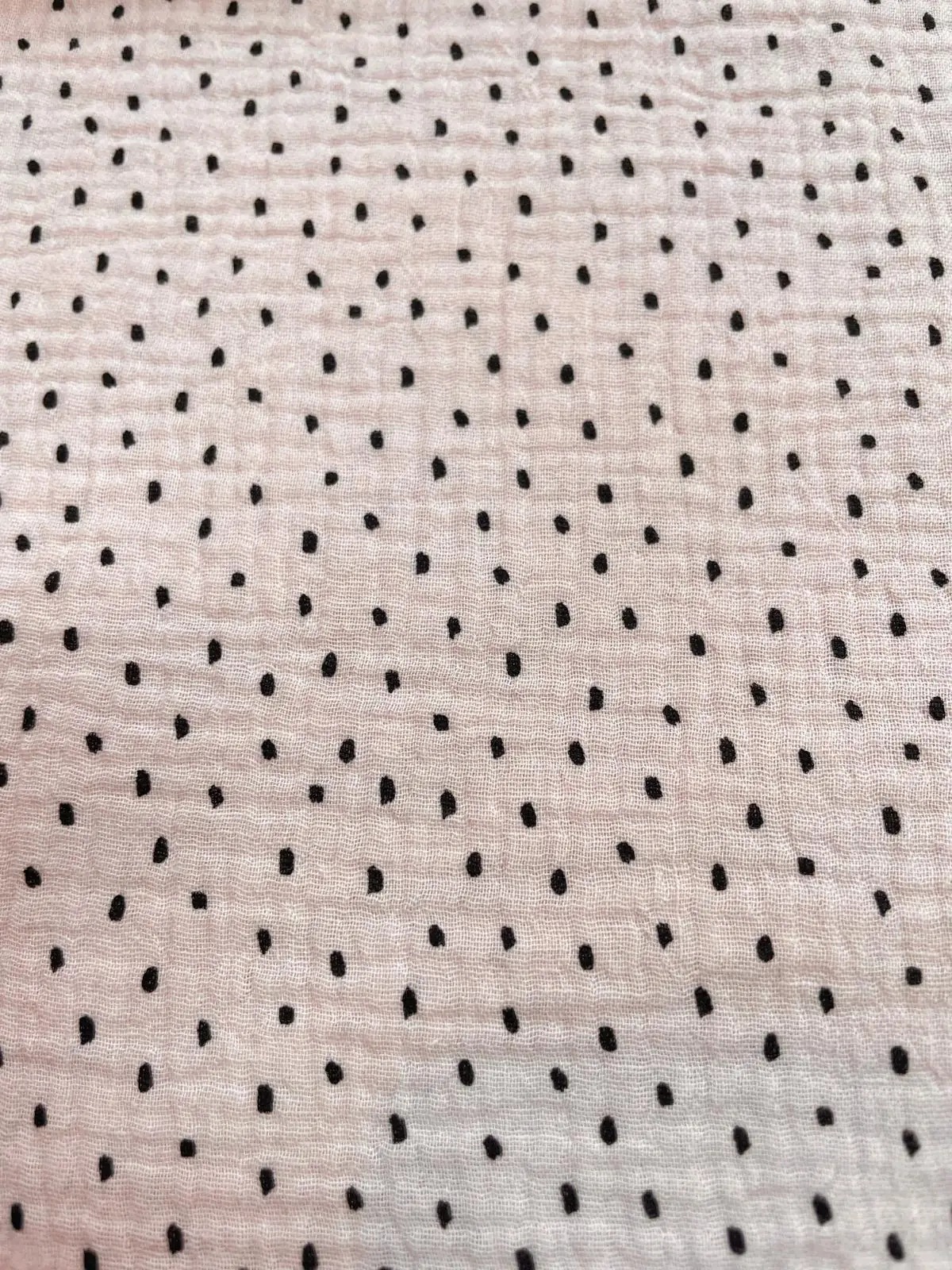Nachhaltiger Bio-Musselin in zartem Hellrosa mit kleinen schwarzen Punkten. Hautfreundliche Baumwoll-Double-Gauze aus biologischem Anbau, ideal für Baby-Accessoires und Mulltücher
