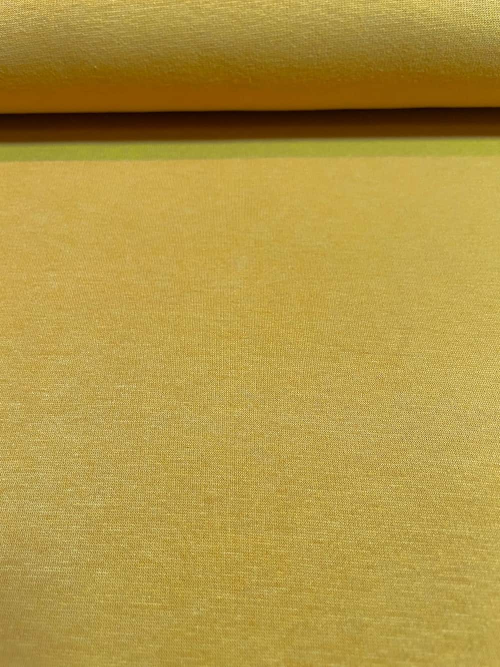 Nahaufnahme von Alpenfleece-Stoff als Meterware in der Farbe Senfgelb mit feiner Oberflächenstruktur