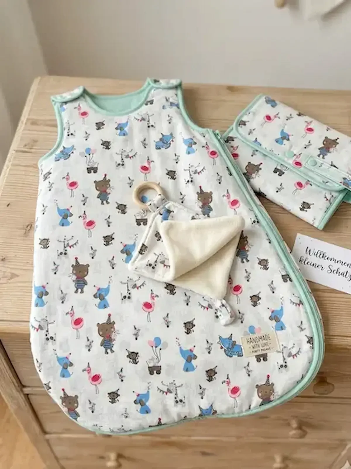 Baby-Erstausstattung Set aus weißer Baumwolle mit bunten Tier-Motiven: Babyschlafsack, Wickeltasche und Schnuffeltuch mit mintgrüner Einfassung