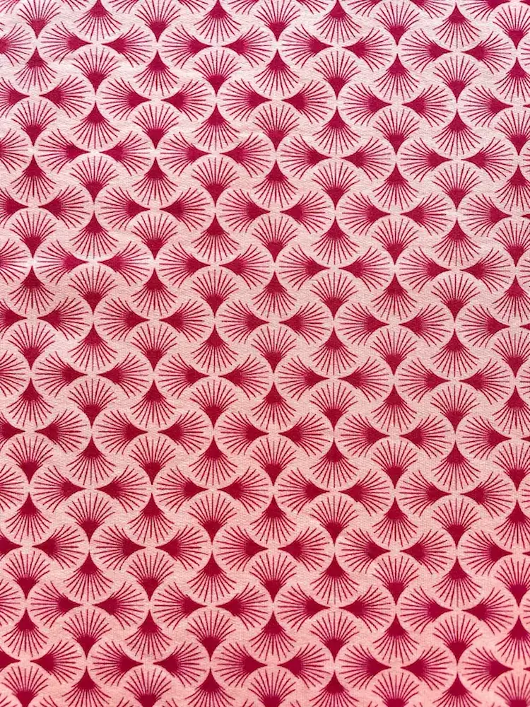 Hochwertiger French Terry Stoff mit geometrischem Fliesenmuster in Altrosa und Beere, flach liegend fotografiert.