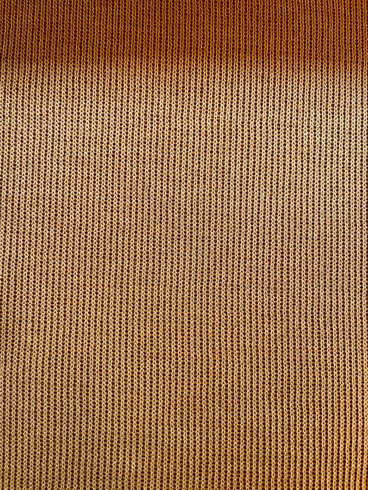 Elastischer Feinstrick-Jersey als Meterware in warmem Ockergelb mit einer feinen, gleichmäßigen Strickstruktur.