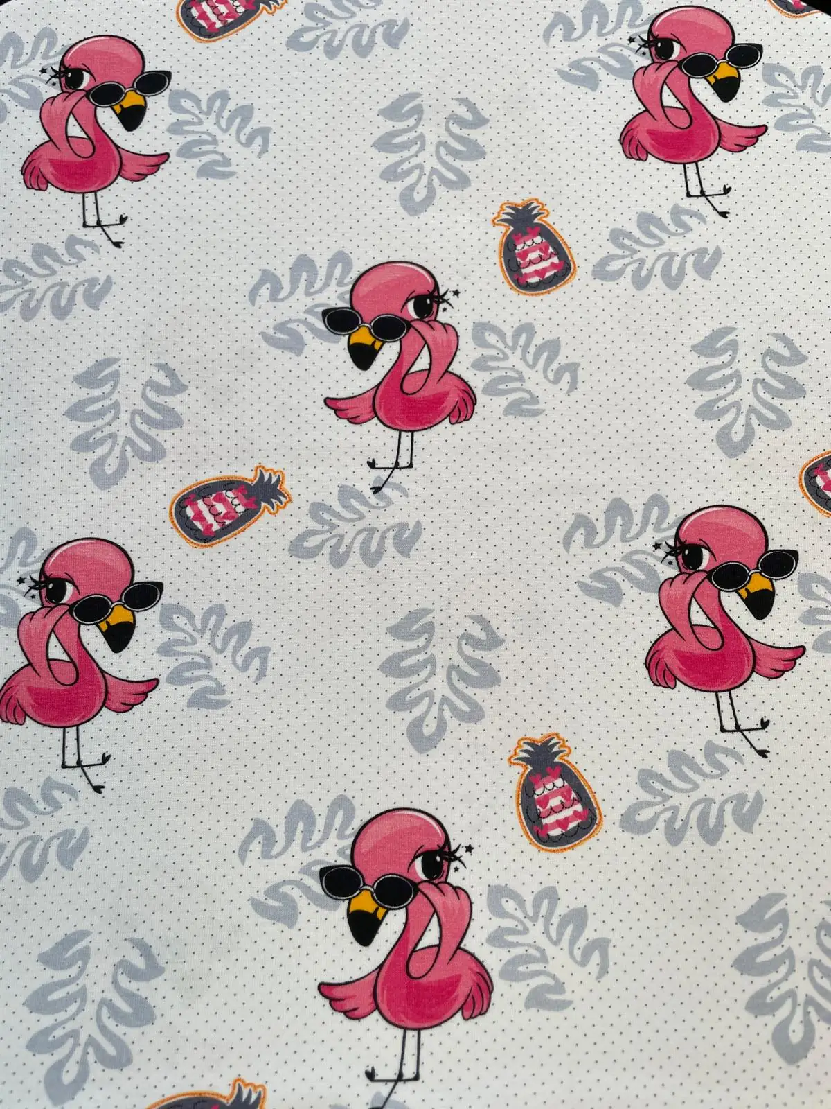 Weißer Jerseystoff mit Punkten als Meterware bedruckt mit pinken Flamingos mit Sonnenbrillen, kleinen Ananas und grauen Blättern.