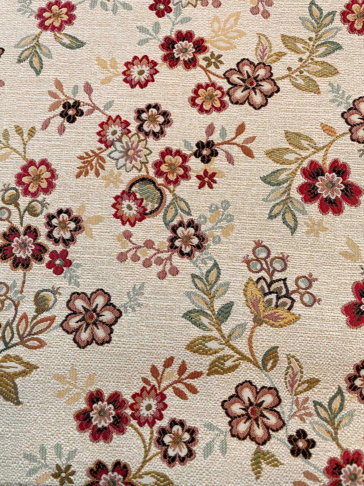 Hochwertig gewebter Gobelinstoff als Meterware mit floralem Jacquard-Muster aus roten, beigen und grünen Blüten auf hellem Grund.