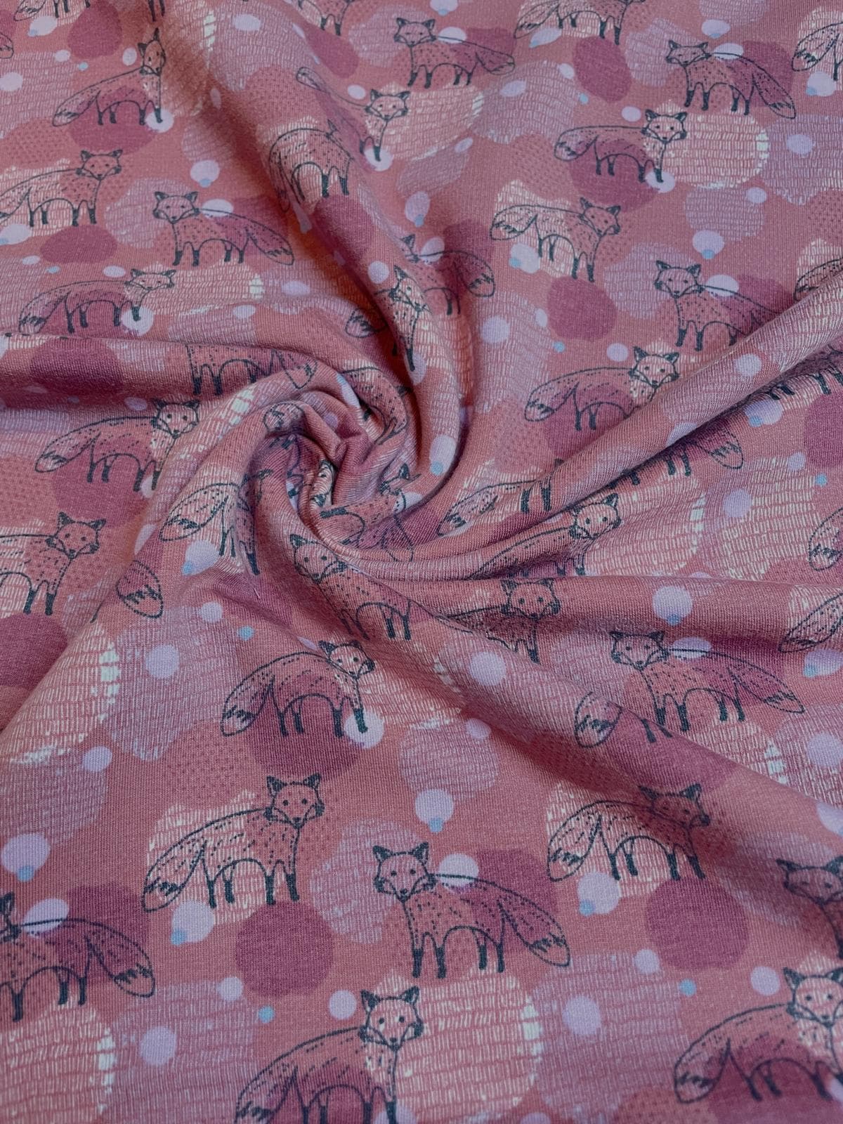 Altrosafarbener Sweatstoff als Meterware mit gezeichneten Fuchs-Motiven und gemusterten Kreisen im Hintergrund, ideal für Kinderkleidung.
