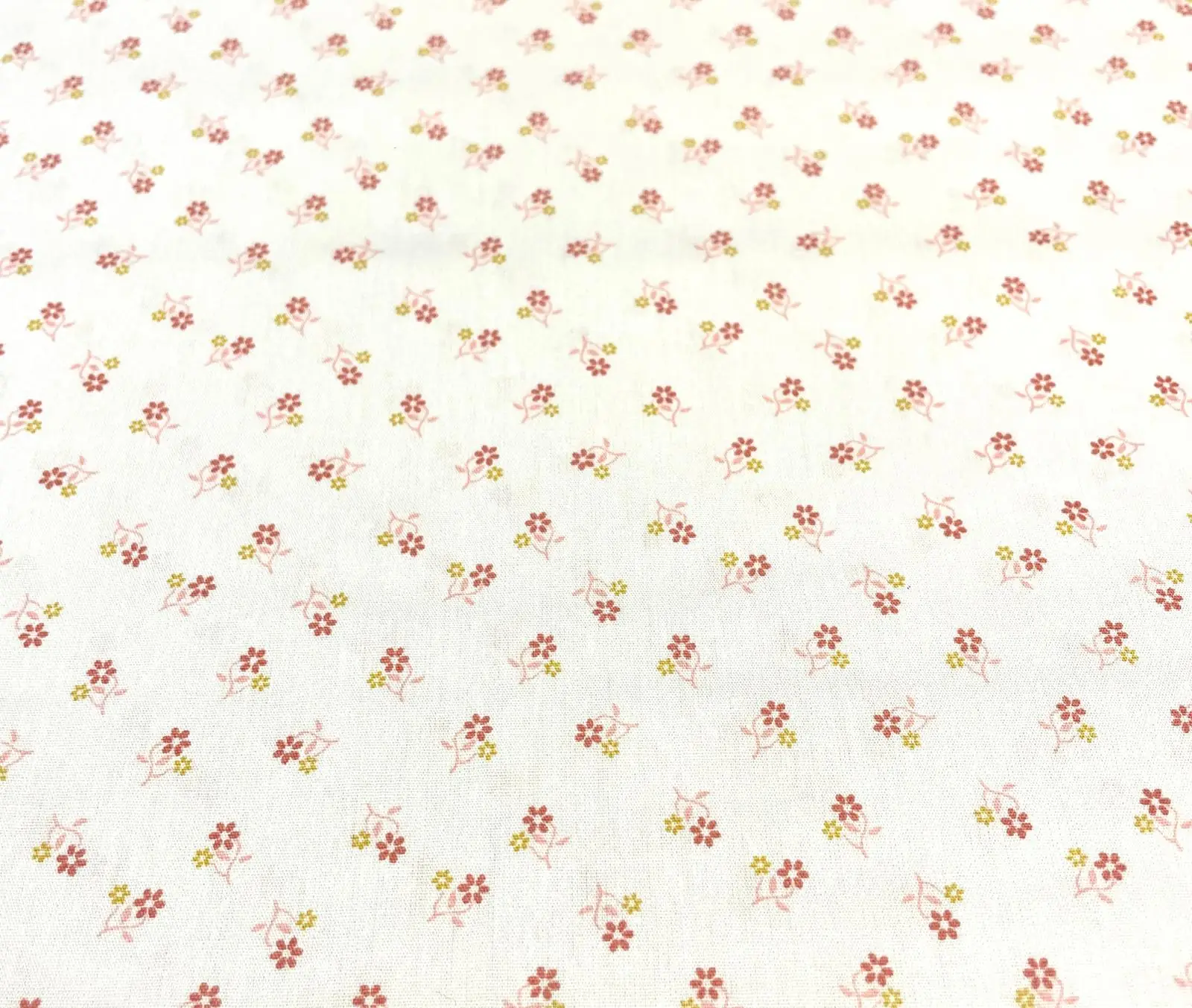 Zarter Baumwoll-Popeline-Stoff als Meterware in Weiß mit kleinen, gestreuten Blumen (Millefleurs-Muster) in Rosa, Rot und Hellgrün.