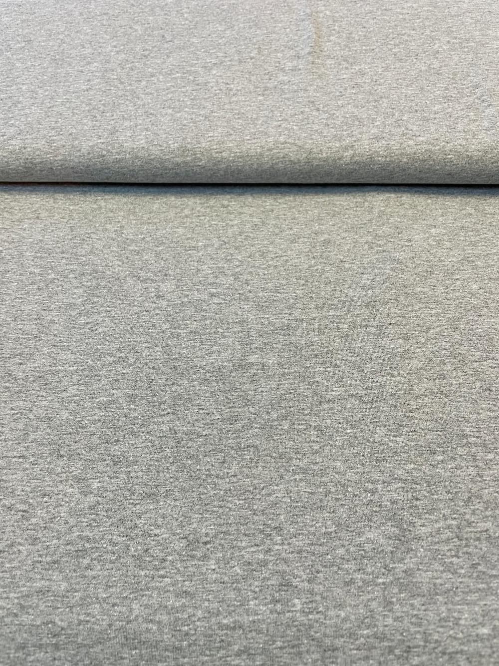 Nahaufnahme eines melierten Jersey-Stoffs aus Baumwolle und Polyester, elastische Meterware für blickdichte Bekleidung.