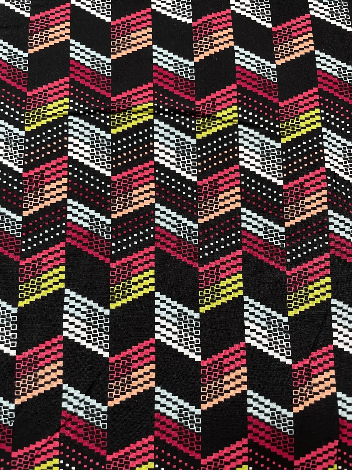 Bedruckter Viskosestoff mit modernem Pixel-Zickzack-Muster in Rot, Gelb, Weiß und Mint auf schwarzem Grund – ideal für fließende Kleider und Blusen.