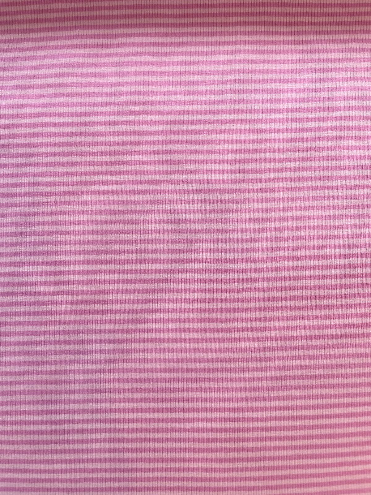 Nahaufnahme von elastischem Baumwolljersey als Meterware mit sehr feinen horizontalen Streifen in Rosa und Hellrosa; weiche, hautfreundliche Qualität für Babykleidung, T-Shirts und Schlafanzüge.