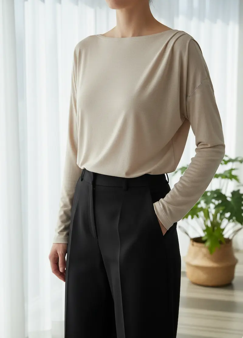 Elegantes Langarmshirt aus naturfarbenem, unbehandeltem Baumwolljersey an einem Model, das den weich fließenden Fall des Stoffes zeigt.