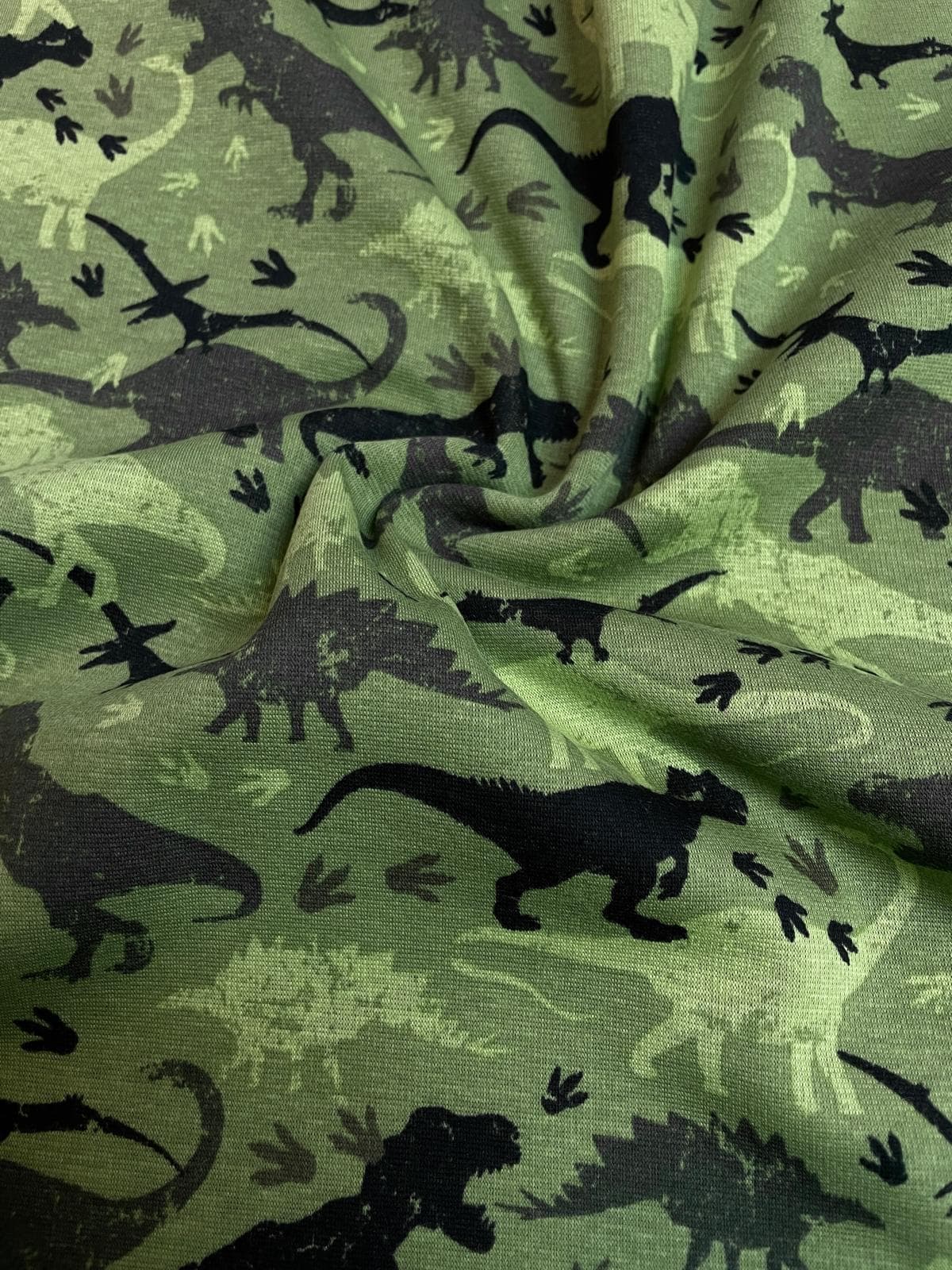 Flauschiger Alpenfleece Stoff in Grün mit Dinosaurier-Motiven, warmer Kuschelsweat für Kinderbekleidung, Meterware.