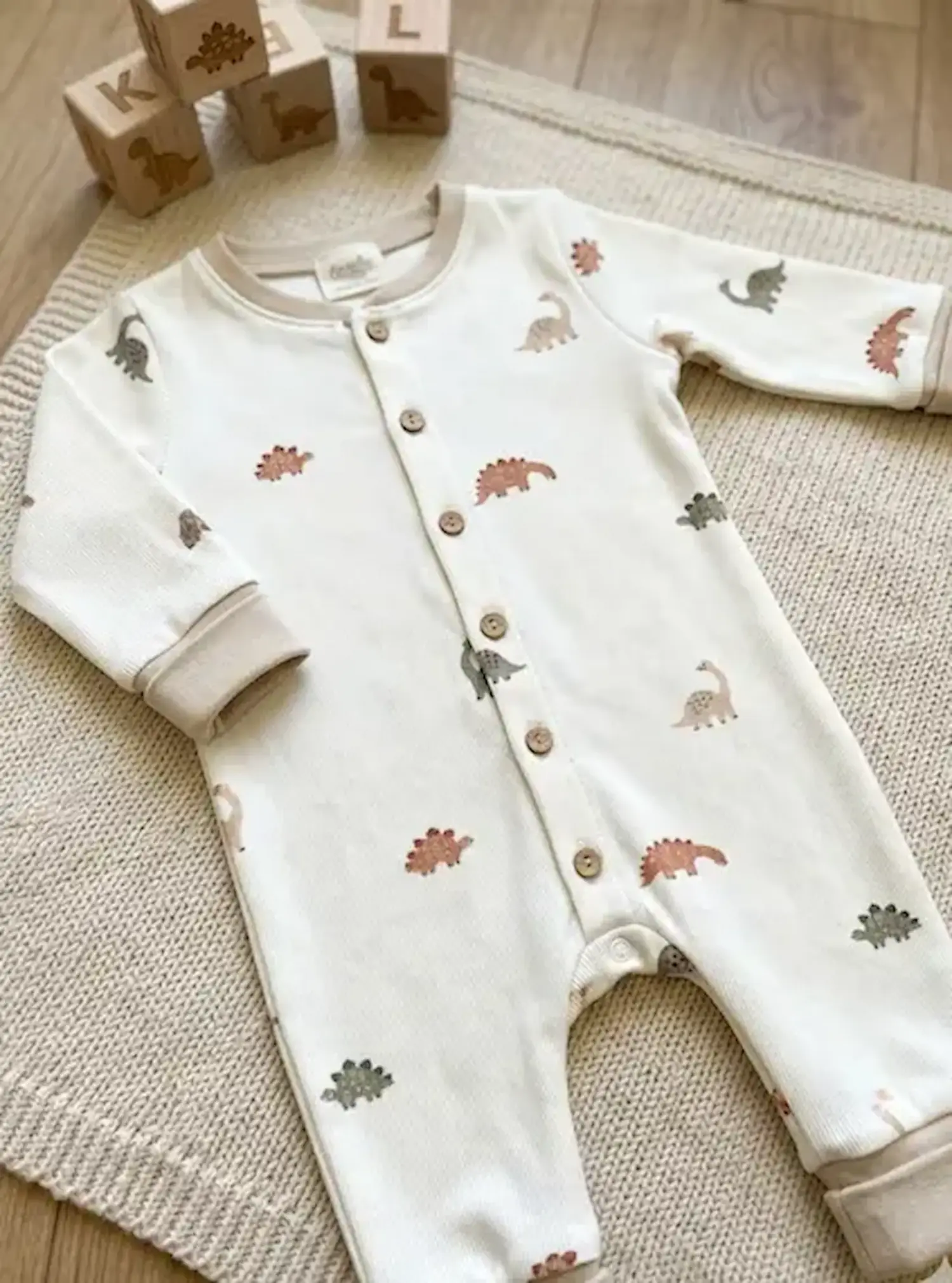 Weißes Kinder-Set aus glattem Jersey-Stoff mit Dinosaurier-Print; Detailansicht der weichen Stoffoberfläche und der Bündchen.