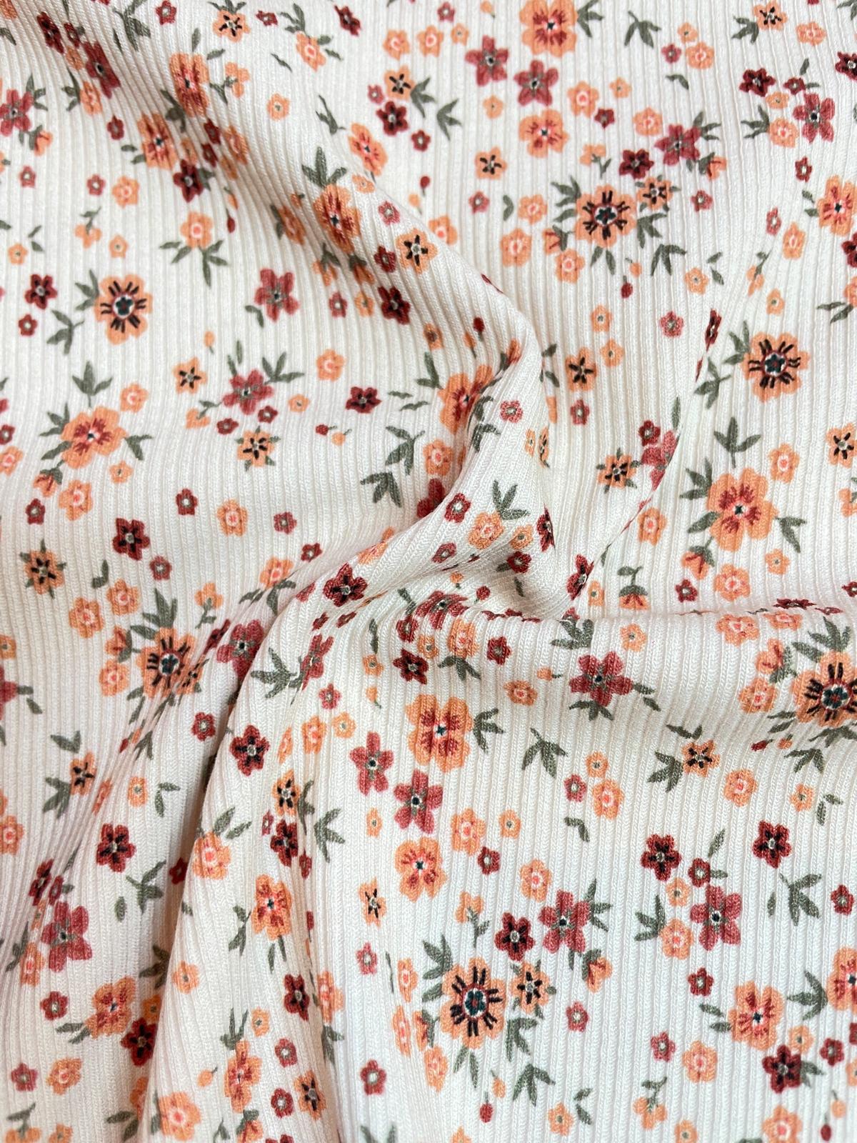 Weicher Rippjersey Stoff mit kleinem Streublumen-Muster in Orange und Rost auf hellem Grund, elastischer Rippstrick für Baby- und Kinderkleidung, Meterware.