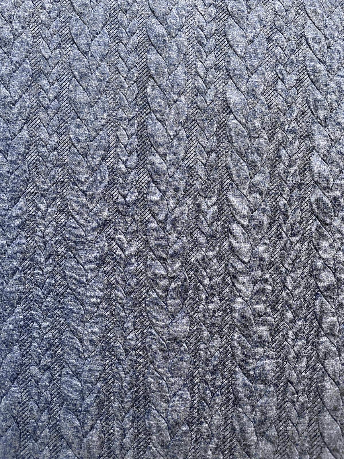 Hochwertiger Jacquard-Strickstoff als Meterware in Jeansblau-Melange mit einem plastisch eingewebten, klassischen Zopfmuster.