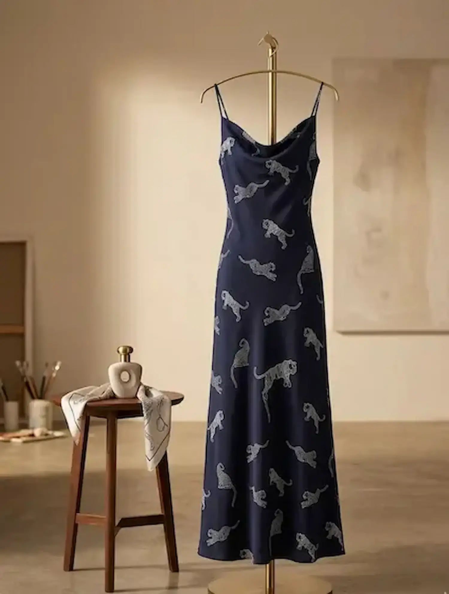Bodenlanges Slip-Dress aus fließendem dunkelblauem Viskose-Stoff mit weißem Tiger-Print auf einer goldenen Schneiderpuppe.
