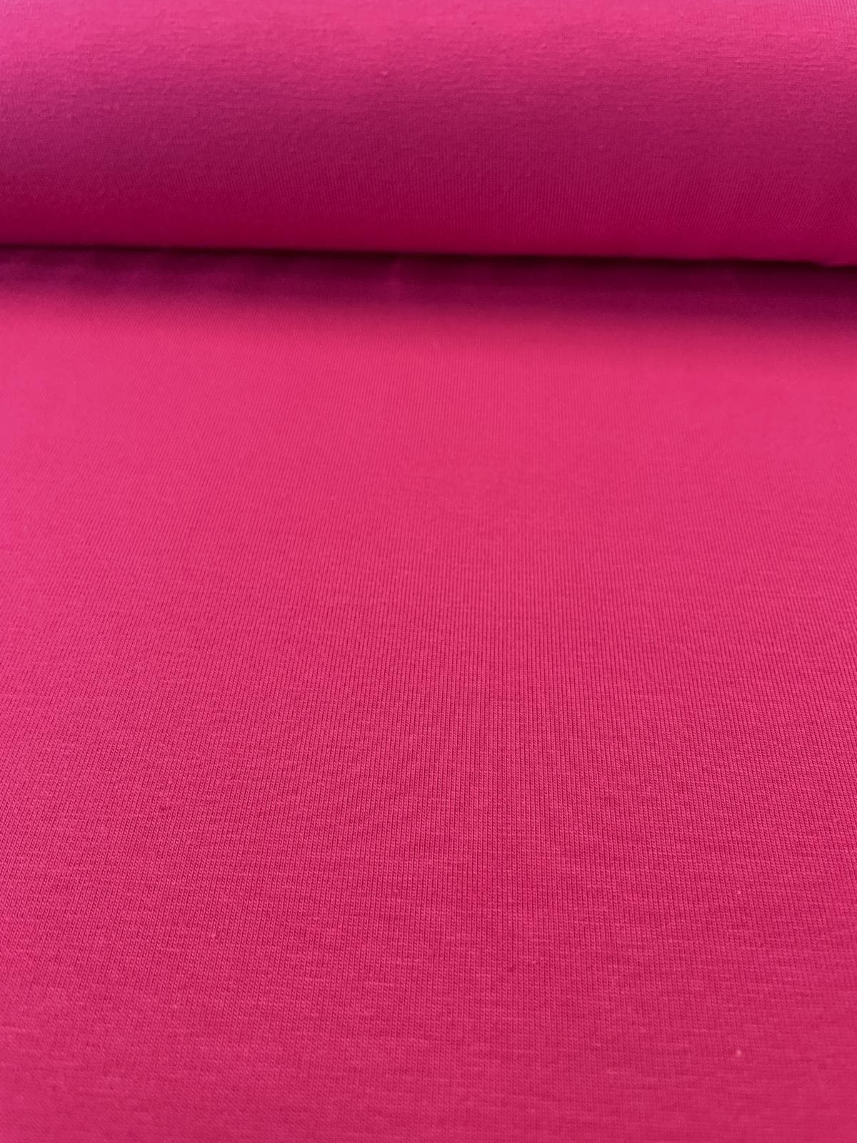 Nahaufnahme von elastischem Baumwolljersey in strahlendem Magenta, glatte Textur, 215g Gewicht, blickdicht.