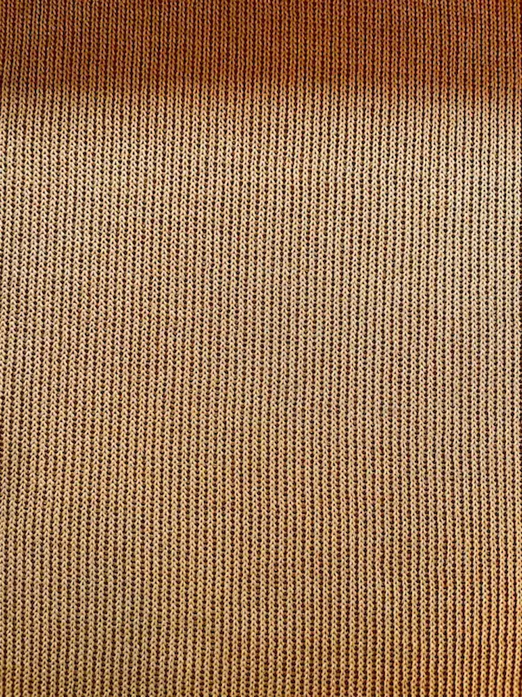 Elastischer Feinstrick-Jersey als Meterware in warmem Ockergelb mit einer feinen, gleichmäßigen Strickstruktur.