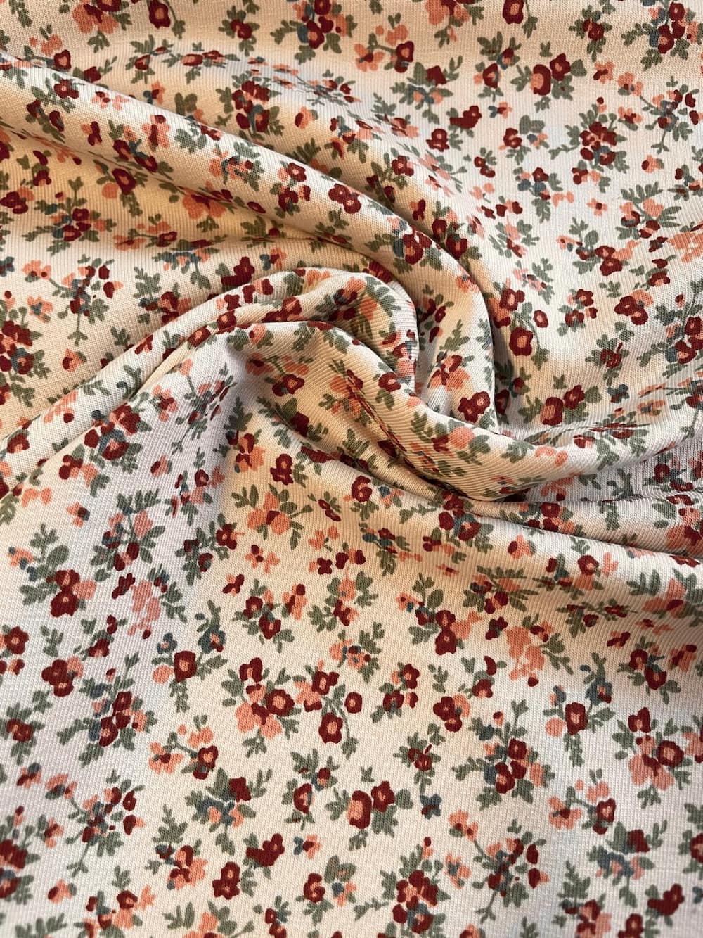 Drapierter French Terry als Meterware mit filigranem Blumenmuster in Rostrot und Grün für Nähprojekte