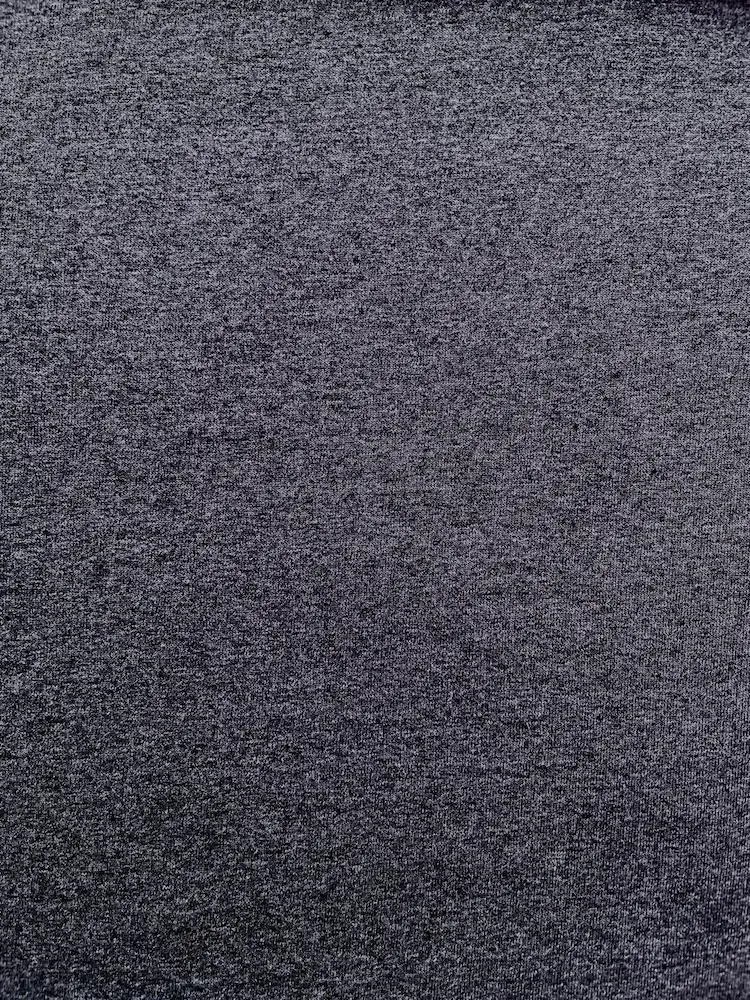 Nahaufnahme der melierten Oberflächenstruktur eines nachhaltigen Jersey-Stoffes in Anthrazit aus recycelter Baumwolle und Polyester.