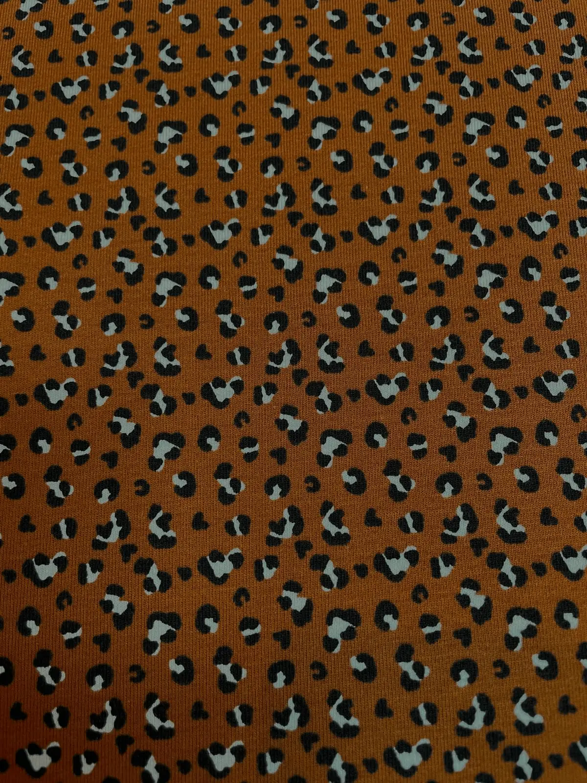 Elastischer Baumwolljersey-Stoff mit modernem Leopard-Print auf ockerfarbenem Grund. Weicher Jersey mit hohem Tragekomfort, ideal für Kinderkleidung, Shirts, Leggings und Beanies.