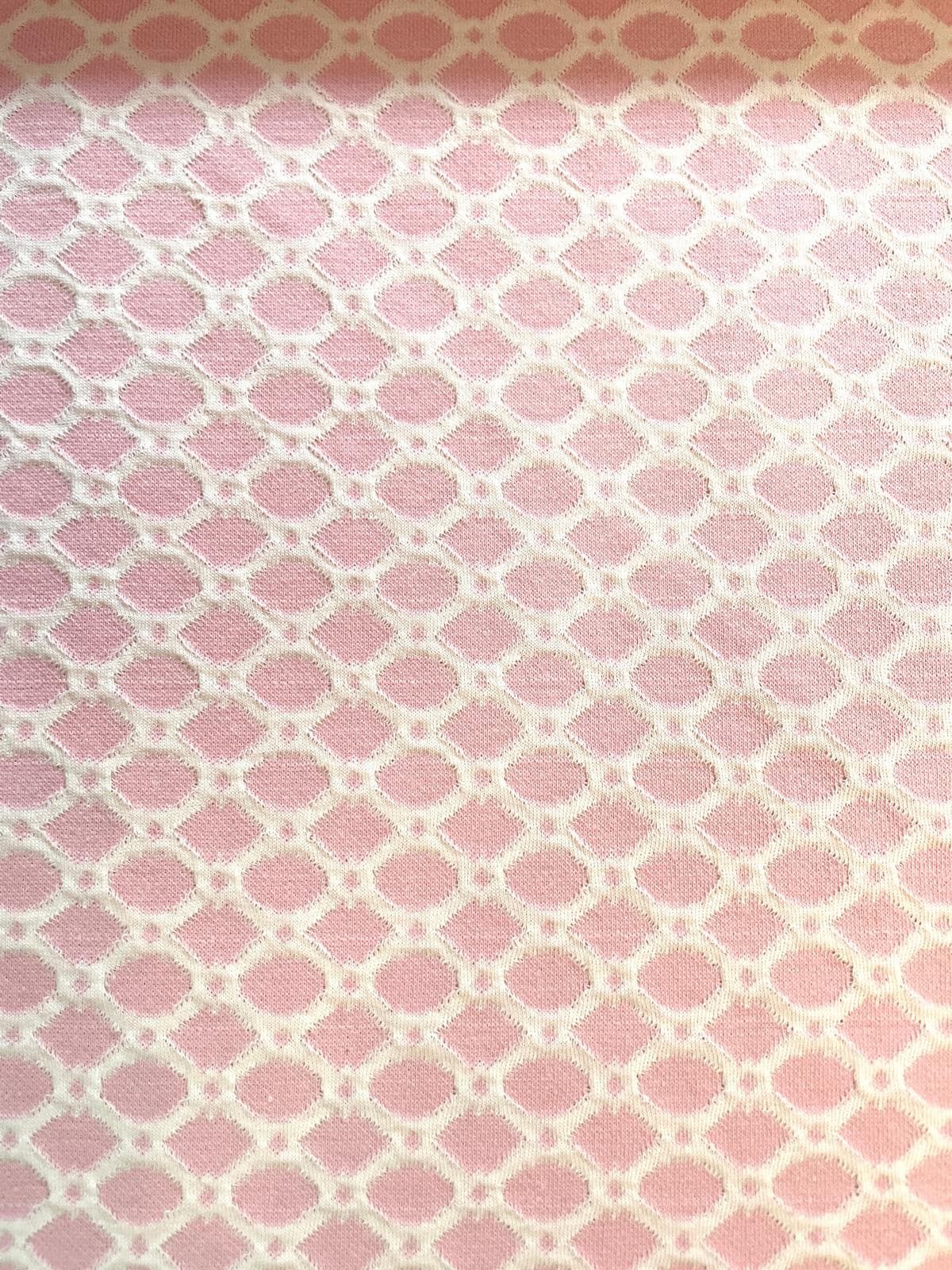 Rosa-weißer Jacquard-Stoff als Meterware mit einem feinen, gleichmäßigen geometrischen Muster aus kleinen Rauten und Kreisen. Die hochwertige Webstruktur des Jacquards ist im Detail zu erkennen.