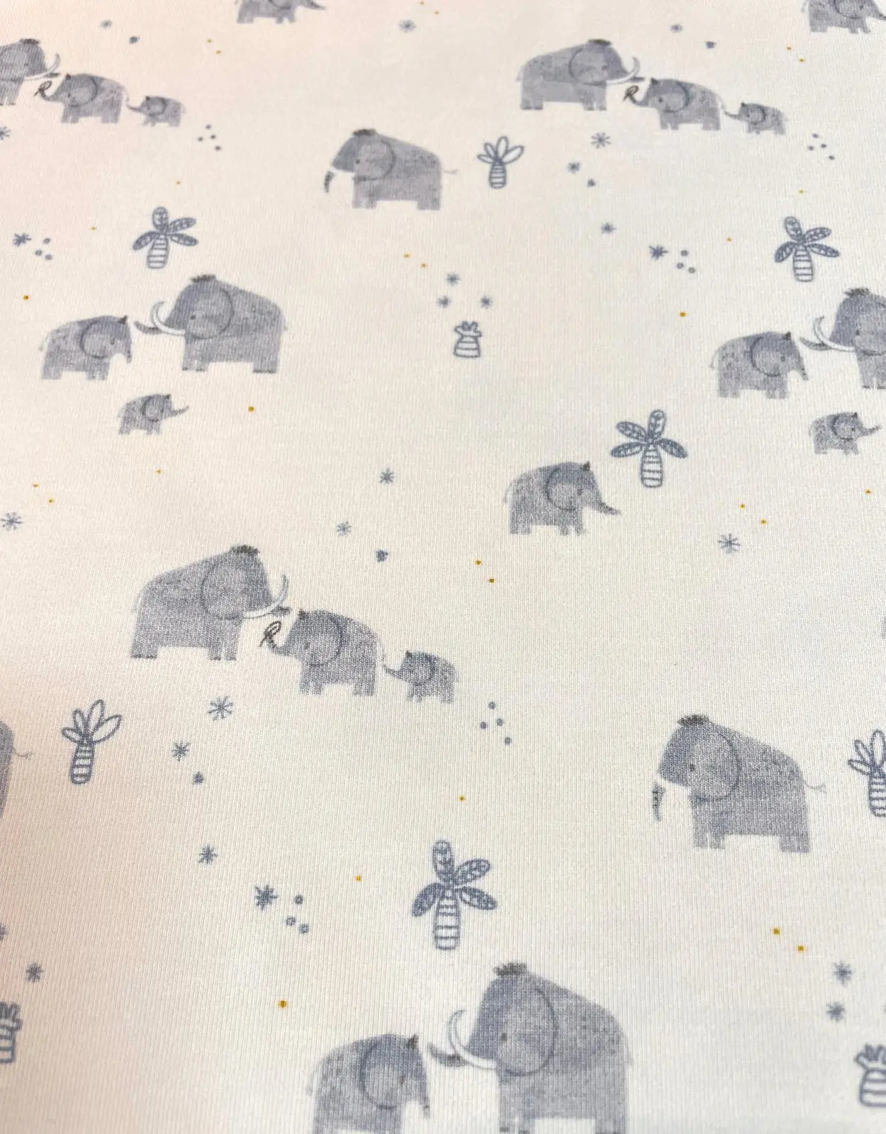 Weicher Jersey-Stoff in Weiß mit graublauen Elefanten-Motiven, kleinen Palmen und Sternen – ideal für maritime oder neutrale Babykleidung.