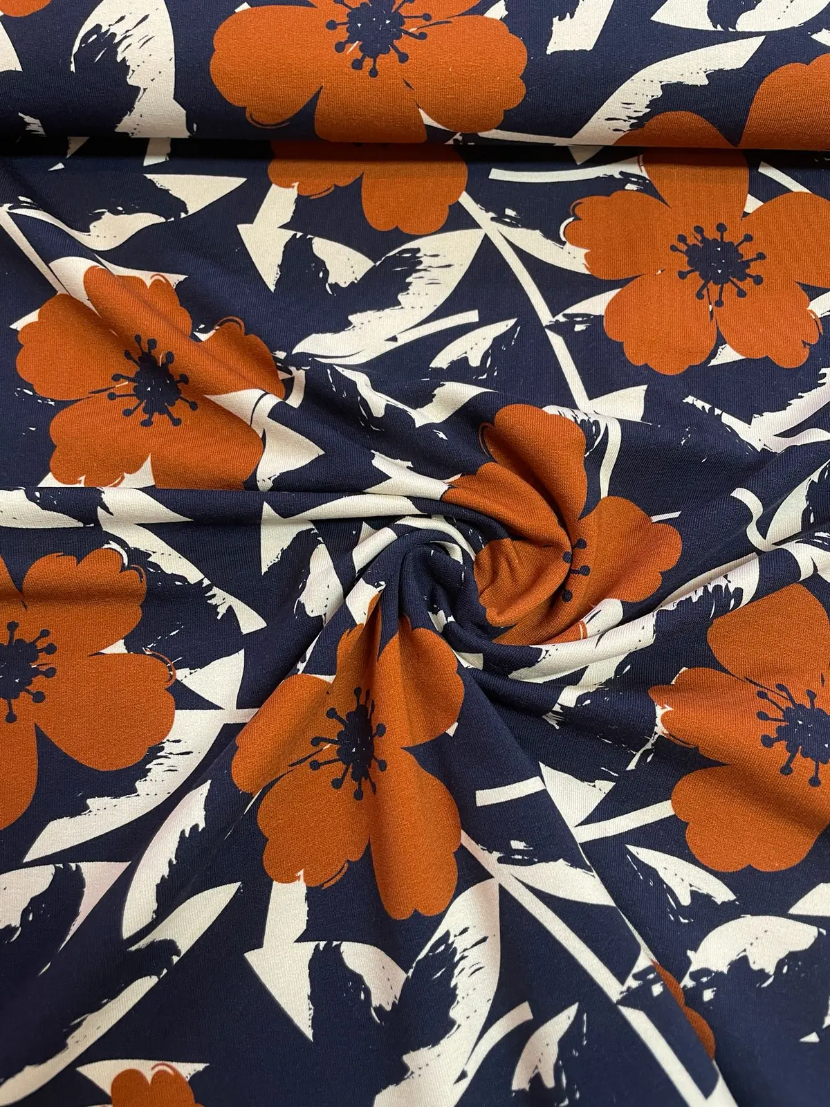 Hochwertiger French Terry Stoff mit großen abstrakten Blumen in Orange auf dunkelblauem Grund, weicher Sommersweat für Damen- und Kinderbekleidung.