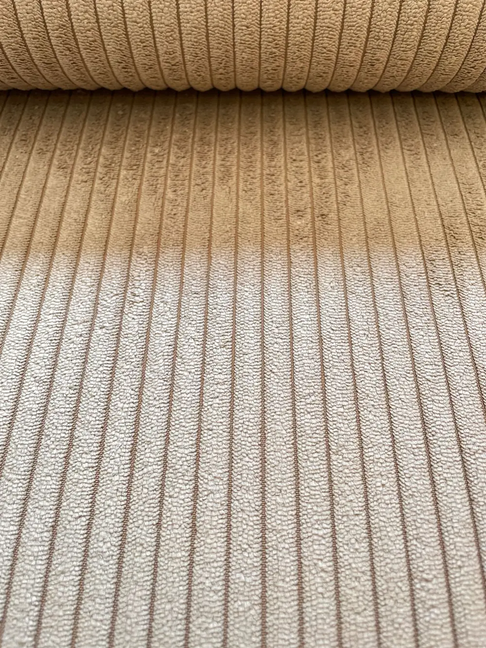 Nahaufnahme eines beigen Breitcord-Stoffs mit charakteristischer Rippenstruktur aus Polyester-Nylon-Mix für Polsterarbeiten und Taschen.