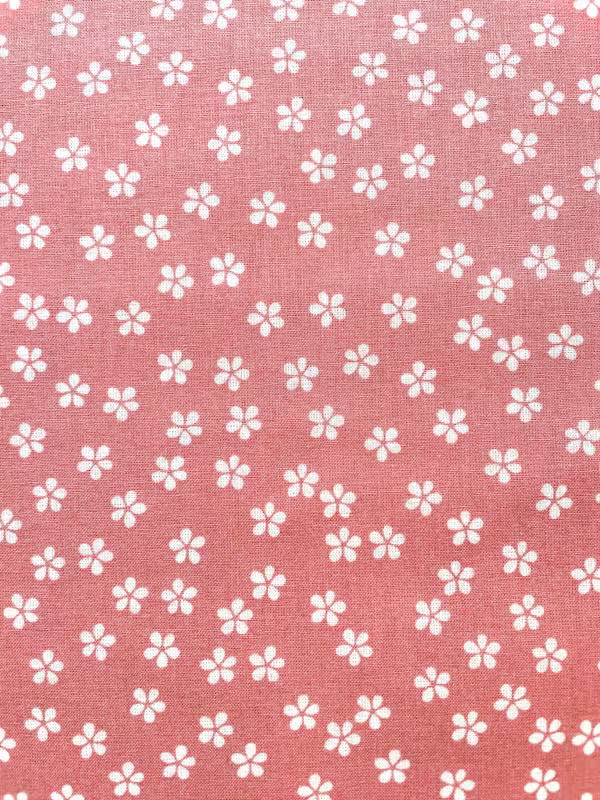 Altrosafarbener Baumwollstoff Popeline mit einem feinen Muster aus kleinen weißen Gänseblümchen.