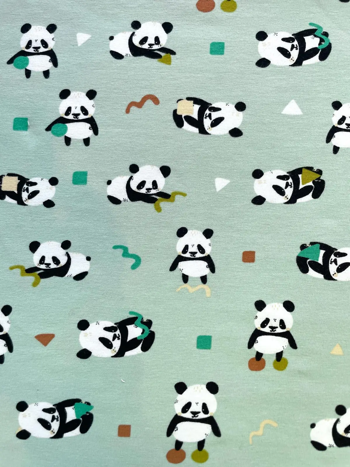 Weicher, elastischer Baumwolljersey in hellem Mintgrün bzw. Salbeigrün, bedruckt mit kleinen, süßen Panda-Bären in verschiedenen Positionen und minimalistischen geometrischen Formen.