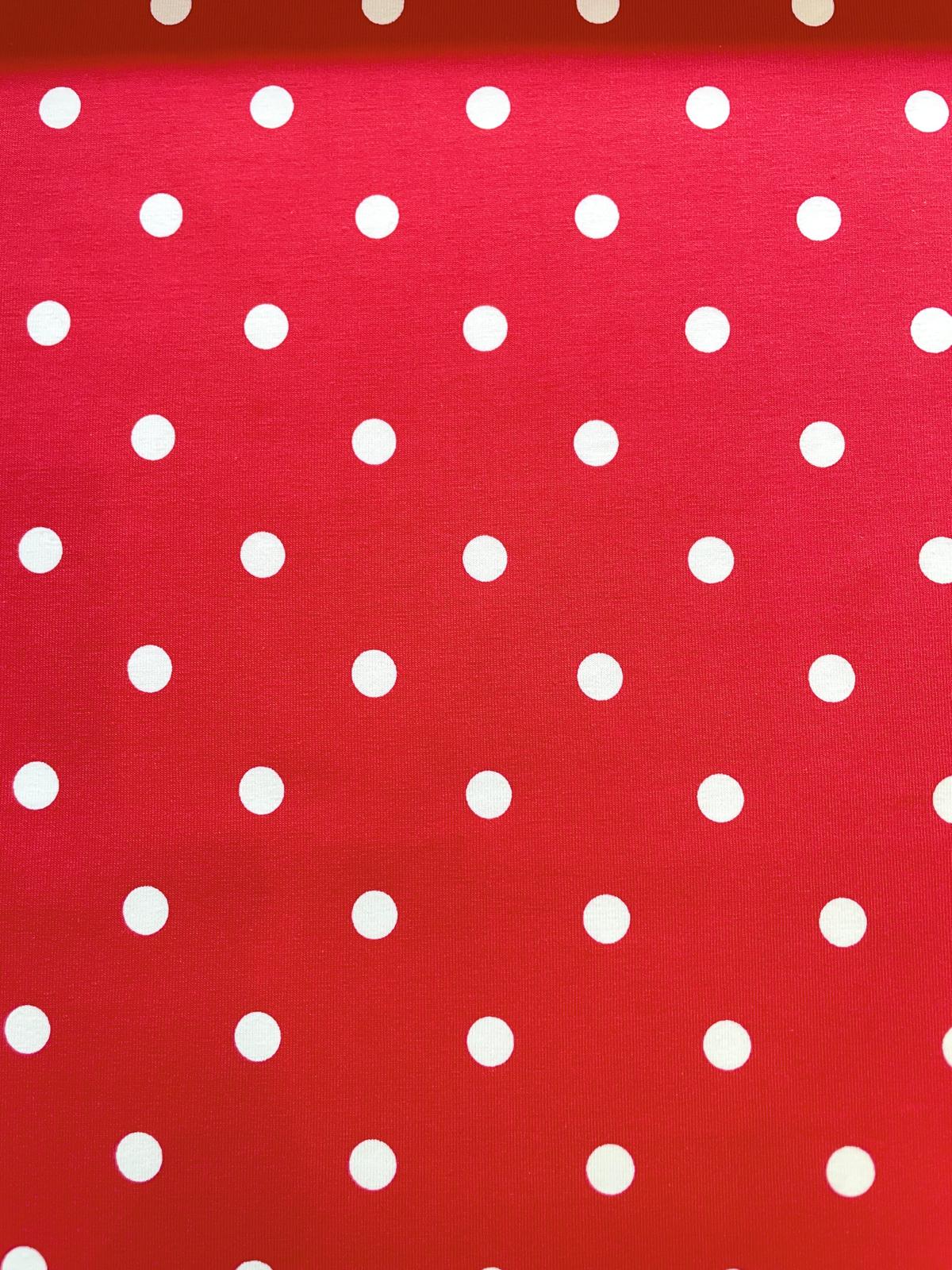 Nahaufnahme eines leuchtend roten Jerseystoffs aus Baumwolle mit einem regelmäßigen Muster aus weißen Punkten (Polka Dots), geeignet als elastische Meterware für Bekleidung.