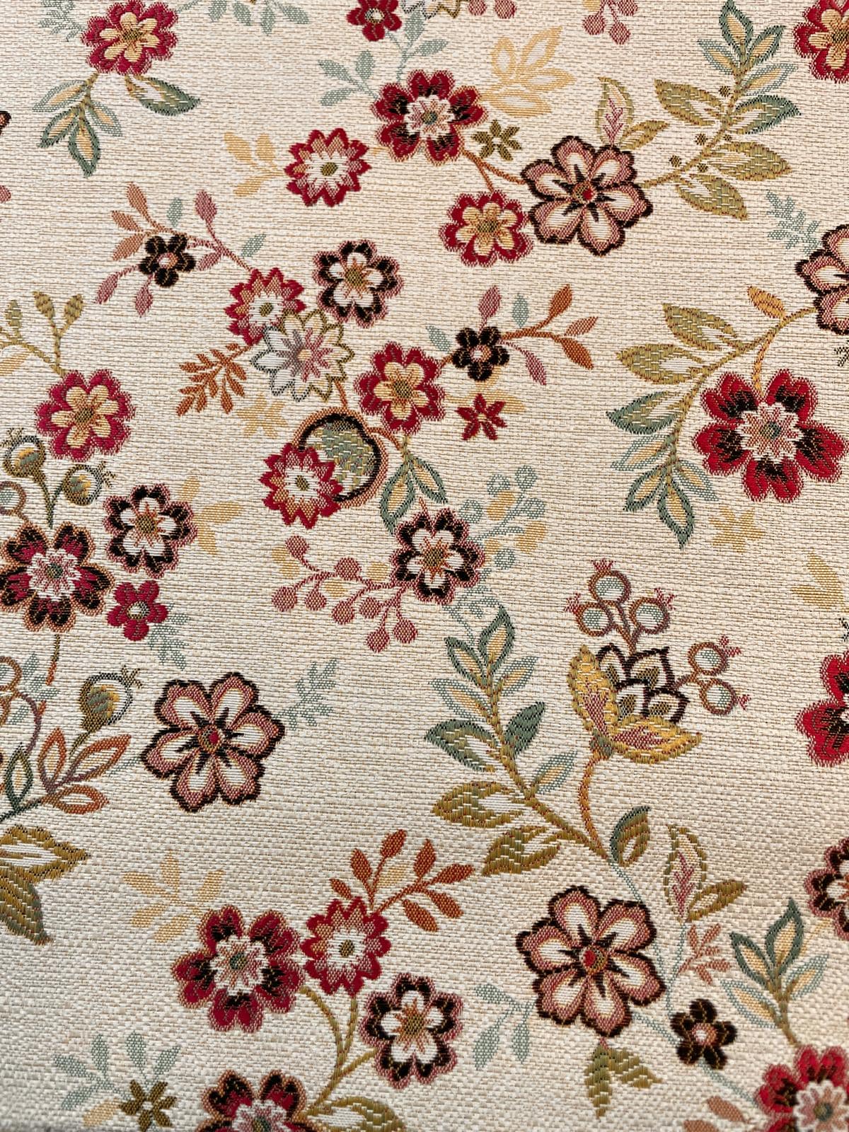 Hochwertig gewebter Gobelinstoff als Meterware mit floralem Jacquard-Muster aus roten, beigen und grünen Blüten auf hellem Grund.