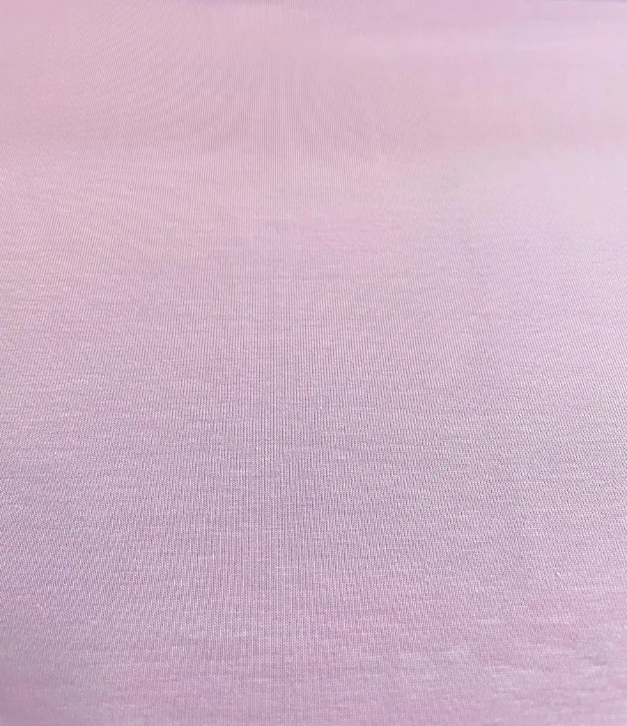 Eine detailreiche Nahaufnahme von einem unifarbenen Baumwolljersey-Stoff als Meterware in einem zarten, hellen Pflaume- oder Fliederton mit einer gleichmäßigen, glatten Oberfläche.