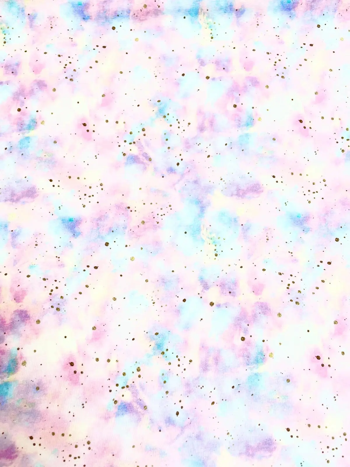 Nahaufnahme eines Jersey-Stoffs mit großem Regenbogen-Motiv in Pastellfarben und feinen goldenen Farbspritzern.