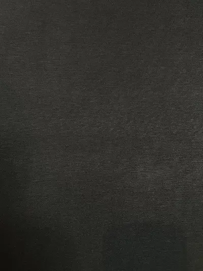 Blick auf die feine Oberflächenstruktur eines tiefschwarzen Interlock-Jerseystoffs. Blickdicht, elastisch und beidseitig glatt gestrickt.