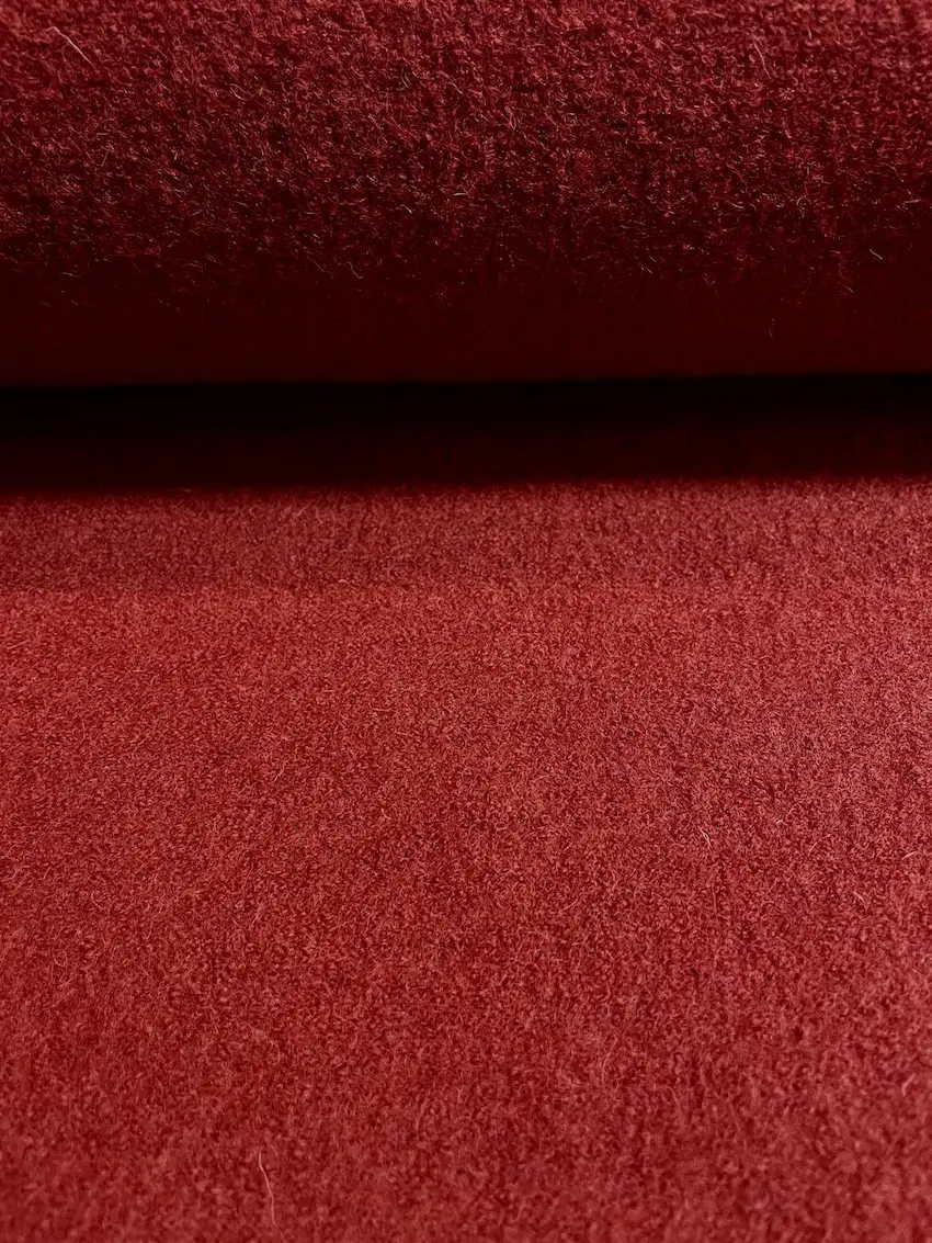 Hochwertiger Walkstoff aus 100% Schurwolle in einem tiefen Rostrot, Nahaufnahme der dichten, gefilzten Textur.