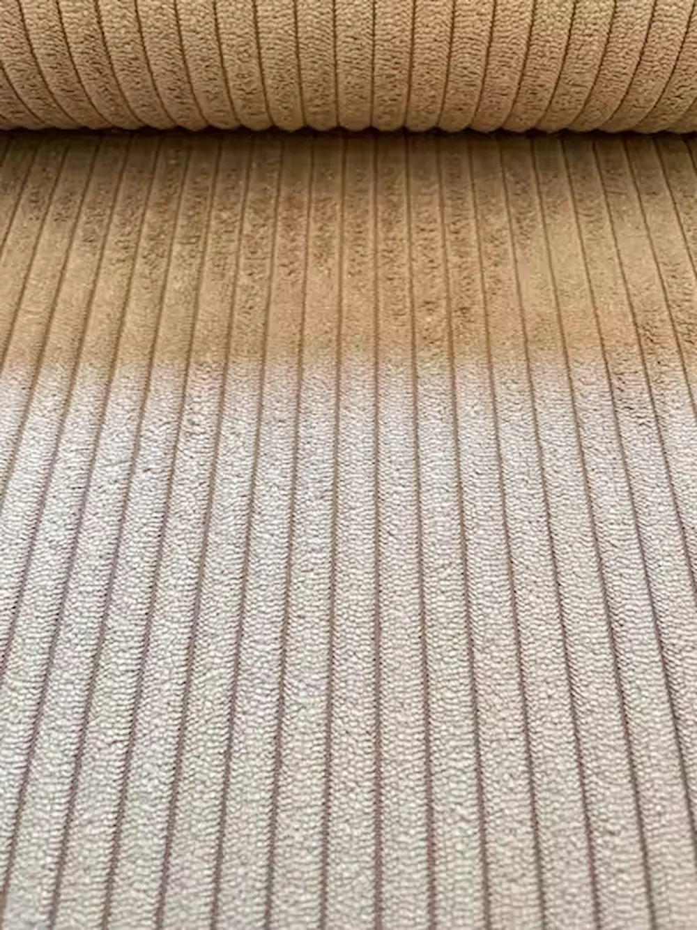 Nahaufnahme eines beigen Breitcord-Stoffs mit charakteristischer Rippenstruktur aus Polyester-Nylon-Mix für Polsterarbeiten und Taschen.