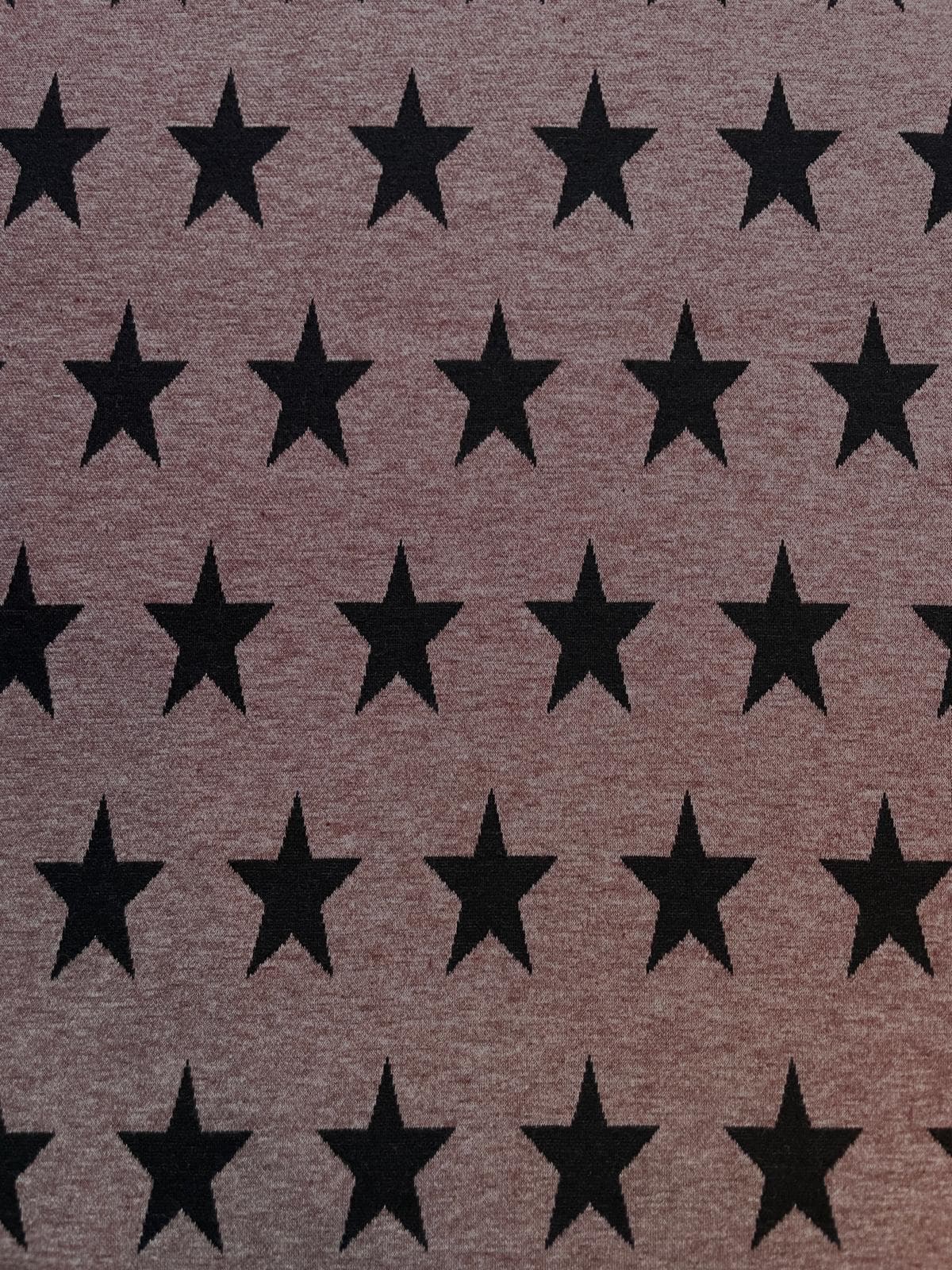 Hochwertiger Jacquard-Stoff als Meterware in meliertem Braun, gleichmäßig gewebt mit einem großflächigen Muster aus markanten schwarzen Sternen. Die feine Strick- bzw. Webstruktur des Materials ist gut erkennbar.
