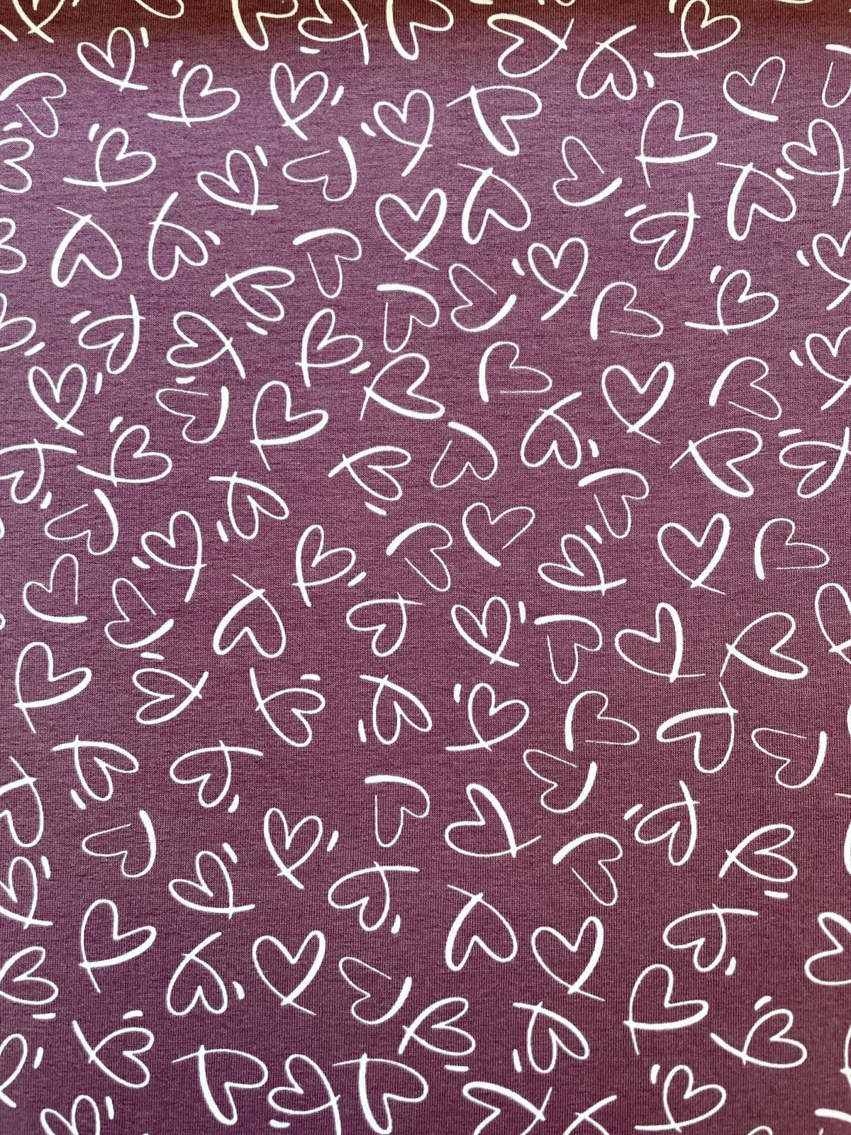 Hochwertiger violetter Jerseystoff mit weißem, handgezeichnetem Herzmuster, Meterware aus 95% Baumwolle für Damen- und Kinderbekleidung.