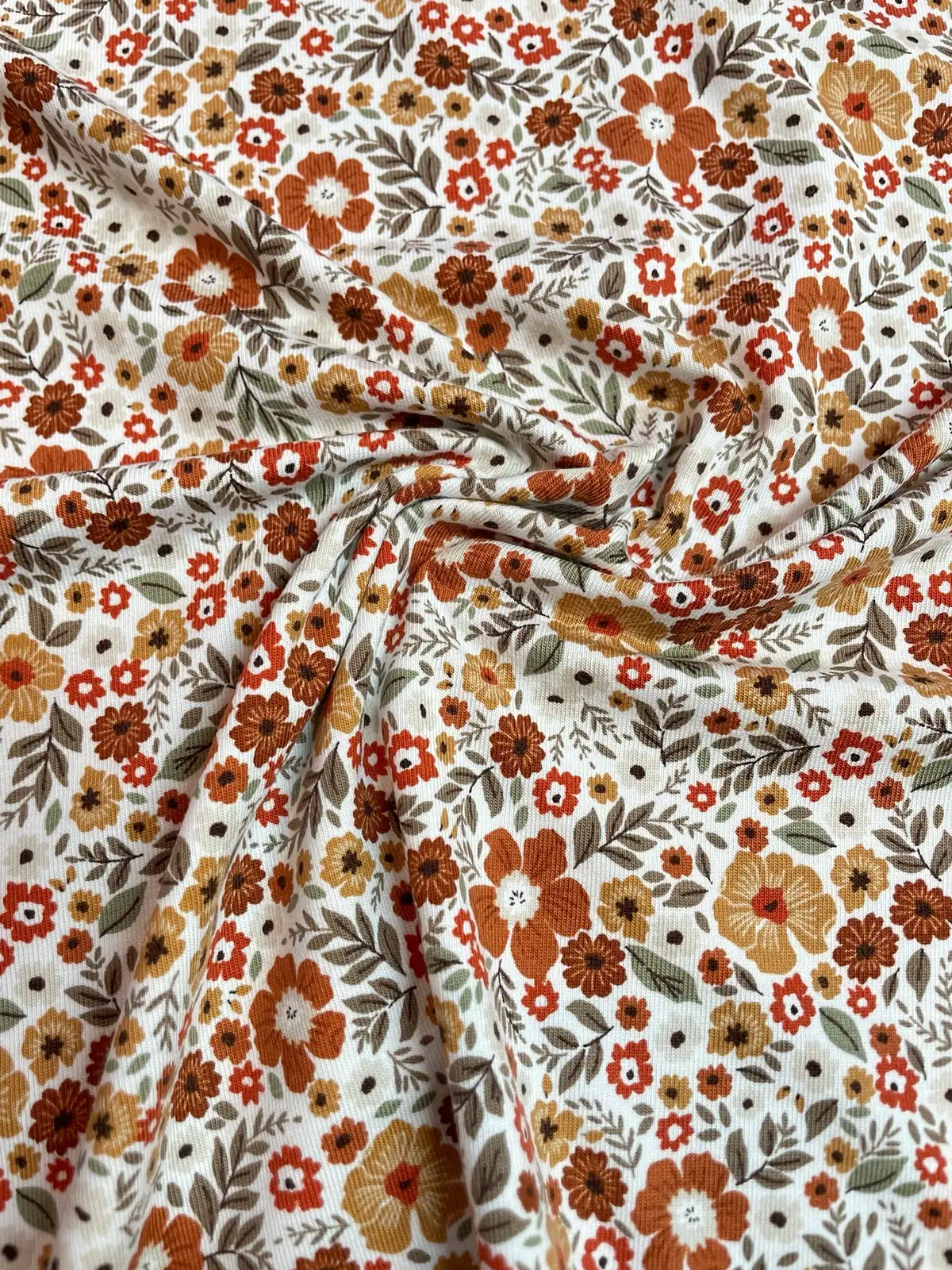 Hochwertiger Jerseystoff mit dichtem floralem Retro-Muster in warmen Erdtönen wie Rost und Ocker, elastische Baumwoll-Meterware für Vintage-Liebhaber.