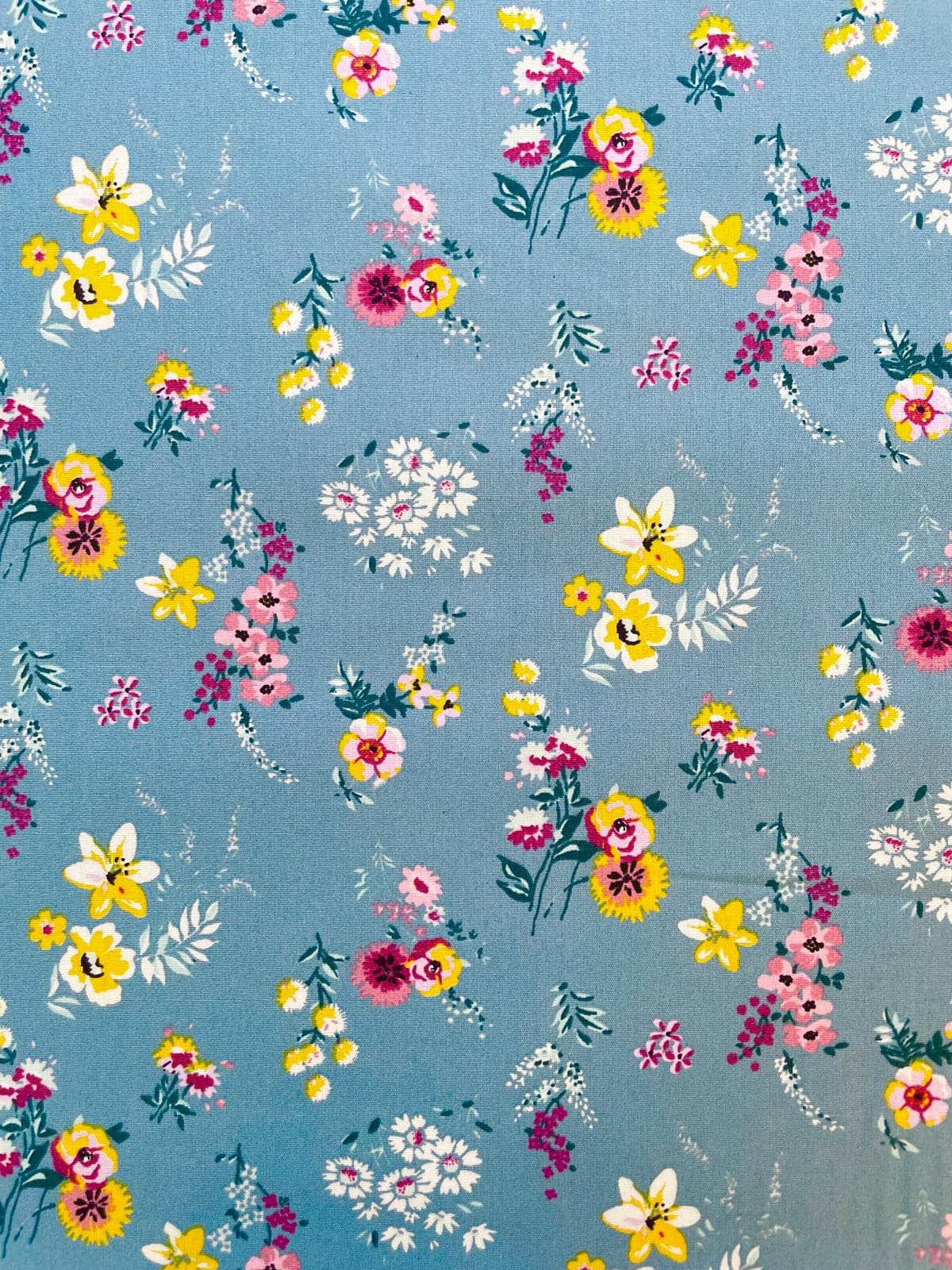 Blauer Baumwollstoff mit bunten Wildblumen in Gelb, Pink und Weiß, hochwertige Webware für sommerliche Nähprojekte.