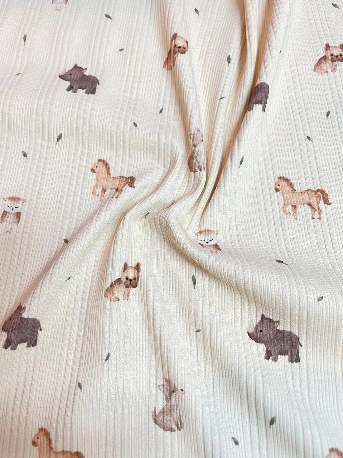 Weicher Rippstrickjersey in Creme als Meterware mit süßen Aquarell-Tiermotiven wie Pferden, Hunden, Eulen und Nashörnern.