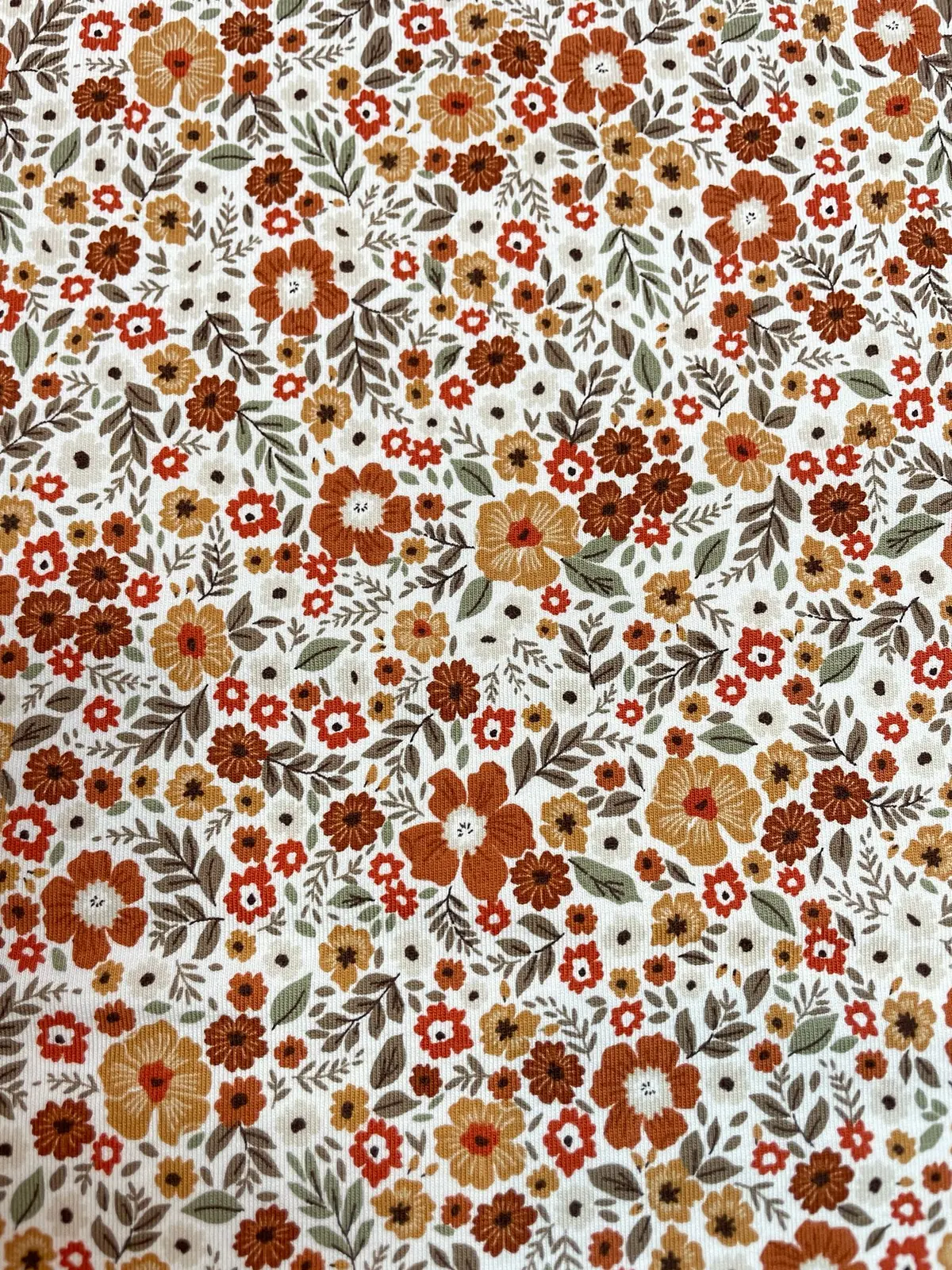 Weicher Jerseystoff mit dichtem Retro-Blumenmuster in Rostrot und Orange, elastische Baumwoll-Meterware für Vintage-Kleider und Accessoires.