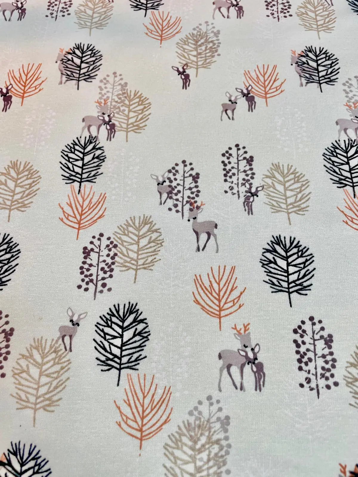Warmer Alpenfleece Doubleface Stoff mit Wald-Motiven; zeigt Rehe und stilisierte Bäume in Rostorange, Taupe und Schwarz auf hellem Grund; ideal für Winter-Hoodies.