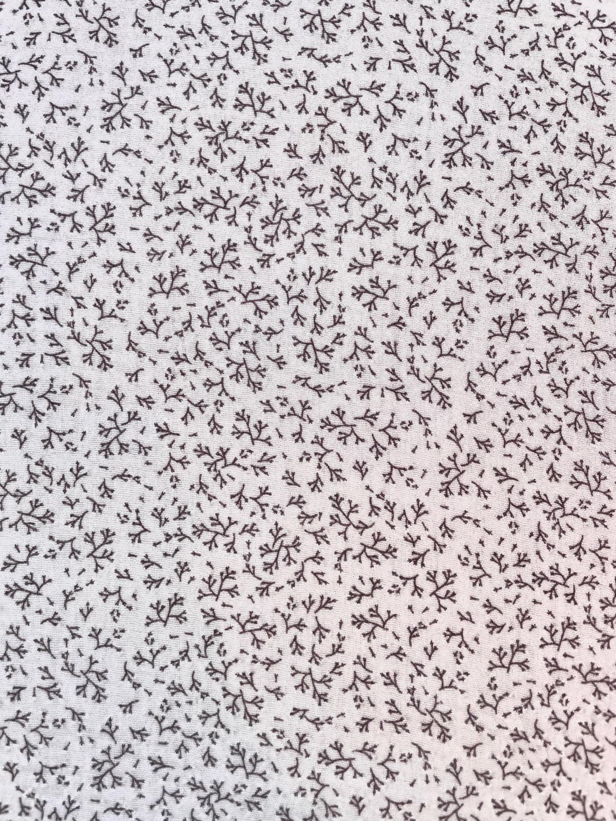 Detaillierte Ansicht von hellem Musselin-Stoff aus 100% Baumwolle mit einem Allover-Print aus kleinen, dunklen Zweigen und Blättern.