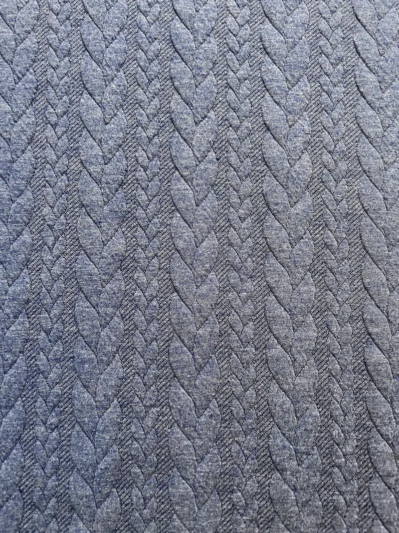 Hochwertiger Jacquard-Strickstoff als Meterware in Jeansblau-Melange mit einem plastisch eingewebten, klassischen Zopfmuster.